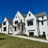 a view of a white house with many windows and a yard