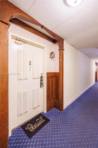 a view of an empty room with kitchen and a window