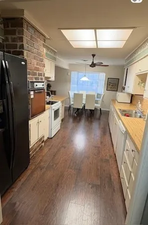 a kitchen with stainless steel appliances granite countertop a stove a sink dishwasher a refrigerator and a dining table with wooden floor