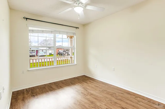 an empty room with wooden floor and windows