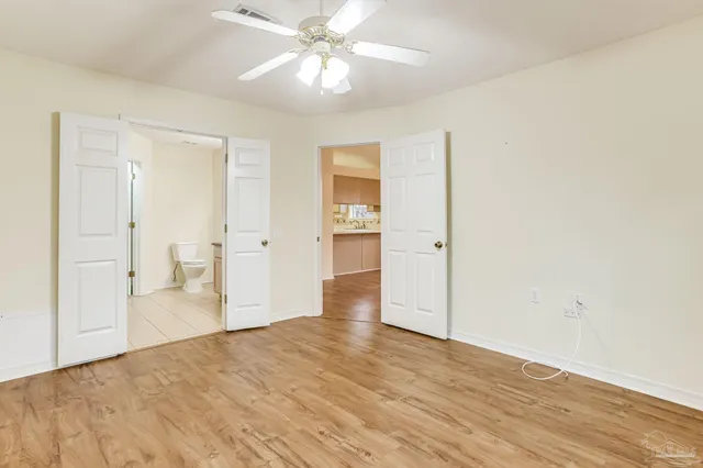 a view of empty room with wooden floor and ceiling fan