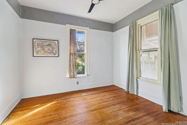 a view of empty room with wooden floor and fan
