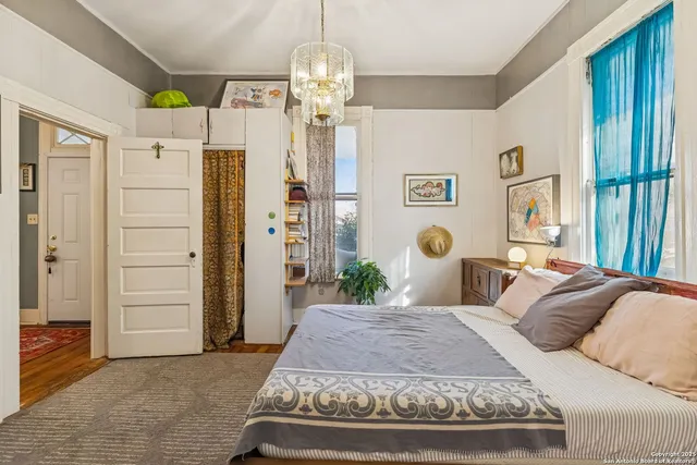 a bedroom with a bed dresser and a chandelier