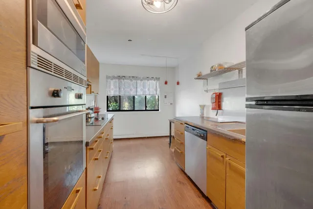 a kitchen with stainless steel appliances granite countertop a refrigerator a stove and a sink with wooden floor