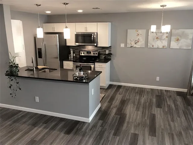 a kitchen with wooden floor and black appliances