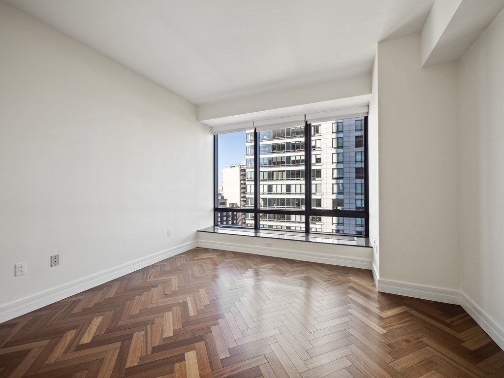 2 Avery Street, Unit 22G Boston, MA 02111 - Photo 19 of 28 an empty room with wooden floor and windows