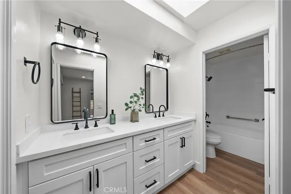 a spacious bathroom with double vanity a toilet a and a mirror
