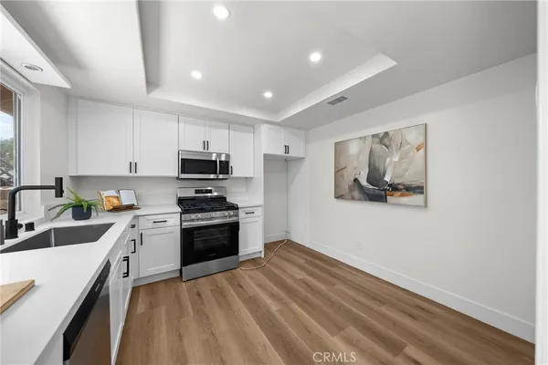 a kitchen with granite countertop white cabinets and stainless steel appliances