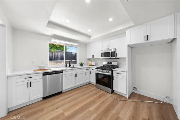 a kitchen with stainless steel appliances granite countertop a stove a sink dishwasher a refrigerator and a oven with wooden floor