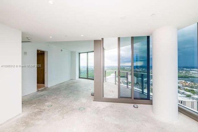 a view of an empty room with wooden floor and fan