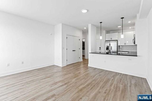 an empty room with wooden floor and a kitchen view