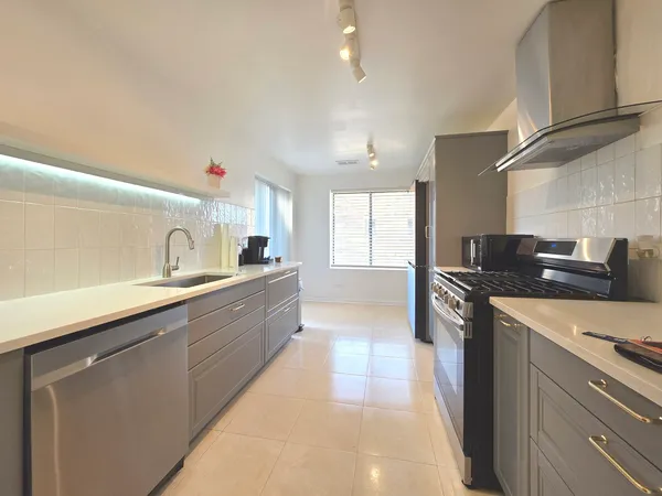 a large kitchen with stainless steel appliances kitchen island granite countertop a sink dishwasher stove and cabinets