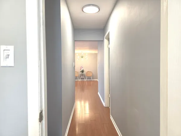 a view of a hallway with wooden floor and a bathroom