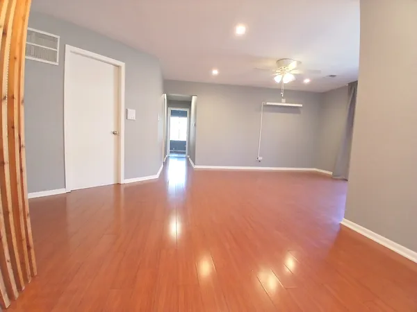 a view of an empty room with wooden floor and a window