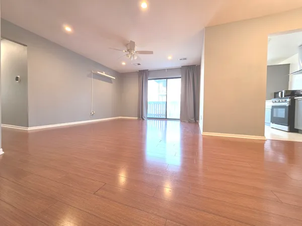 a view of an empty room with kitchen and a window