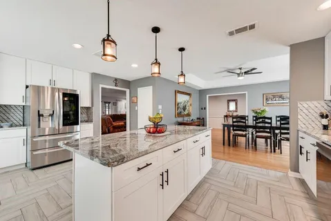 a large kitchen with kitchen island a large counter space a sink appliances and living room view