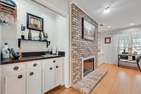 a living room with stainless steel appliances furniture a fireplace and a flat screen tv