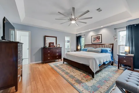a spacious bedroom with a bed a dresser and a large mirror