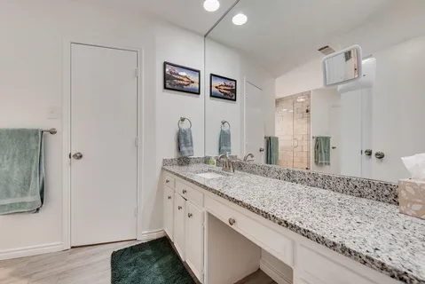 a bathroom with a granite countertop double vanity and a mirror
