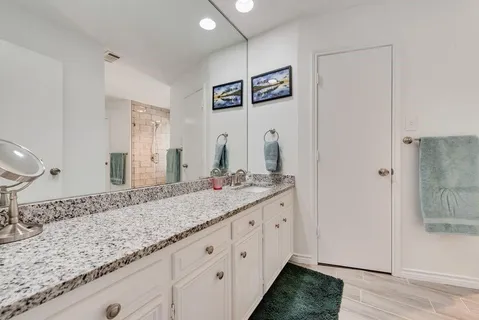 a bathroom with a granite countertop double vanity sink and a mirror