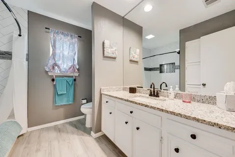 a en suite bathroom with a granite countertop toilet sink and mirror