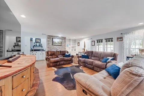 a living room with furniture kitchen view and a window