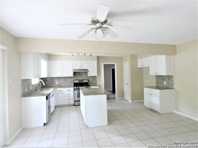 a large kitchen with granite countertop a stove sink and cabinets