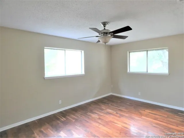 an empty room with wooden floor and windows