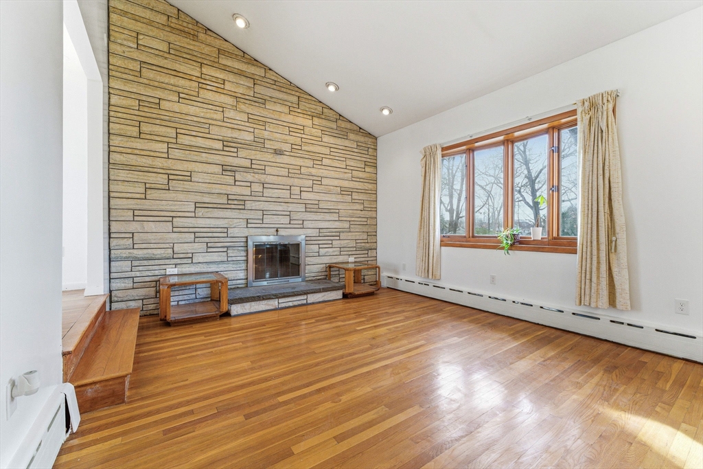 7 Carol Street Stoneham, MA 02180 - Photo 6 of 28 a view of a livingroom with wooden floor and a fireplace
