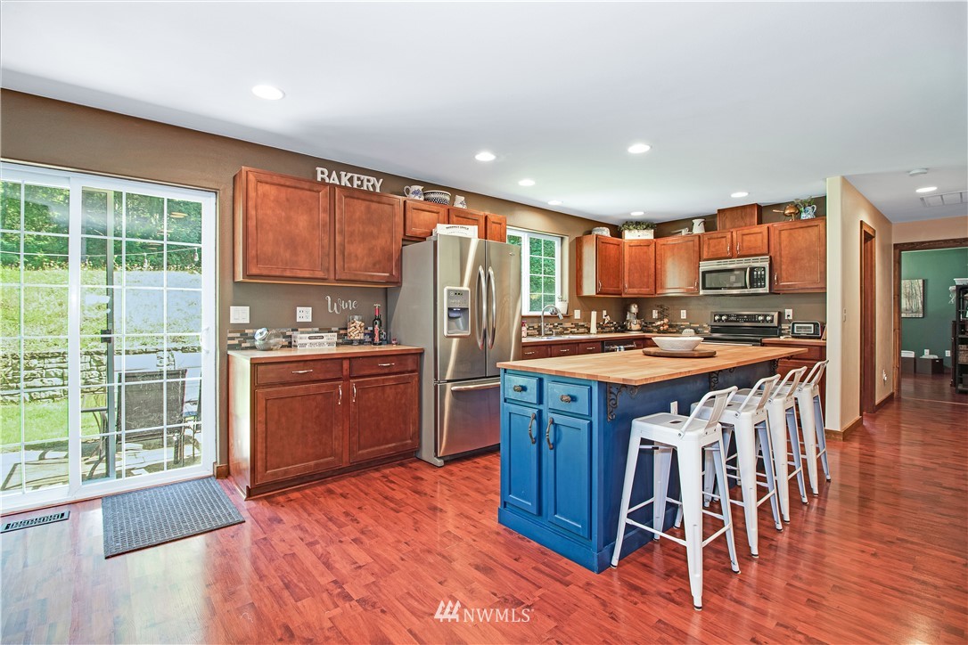 16704 Sargent Road Southwest Rochester, WA 98579 - Photo 11 of 40 a kitchen with stainless steel appliances kitchen island granite countertop wooden floors and a view of living room