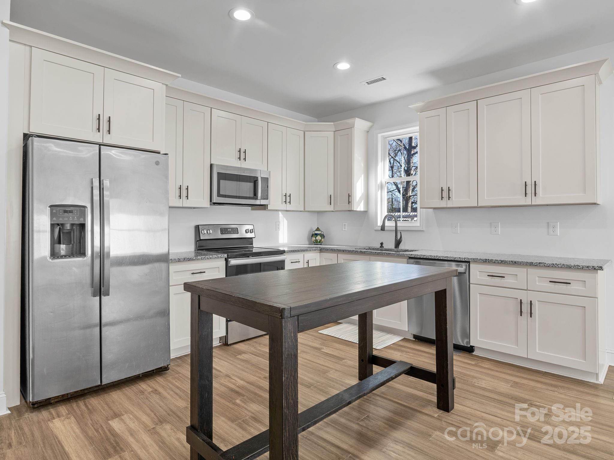 409 South Lyles Avenue Landrum, SC 29356 - Photo 11 of 36 a kitchen with stainless steel appliances granite countertop a refrigerator a stove a sink and white cabinets with wooden floor