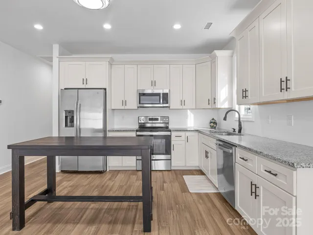 a kitchen with granite countertop white cabinets and white appliances