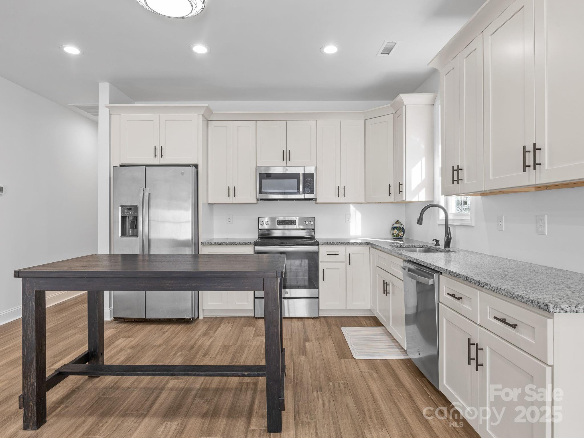 409 South Lyles Avenue Landrum, SC 29356 - Photo 12 of 36 a kitchen with granite countertop white cabinets and white appliances