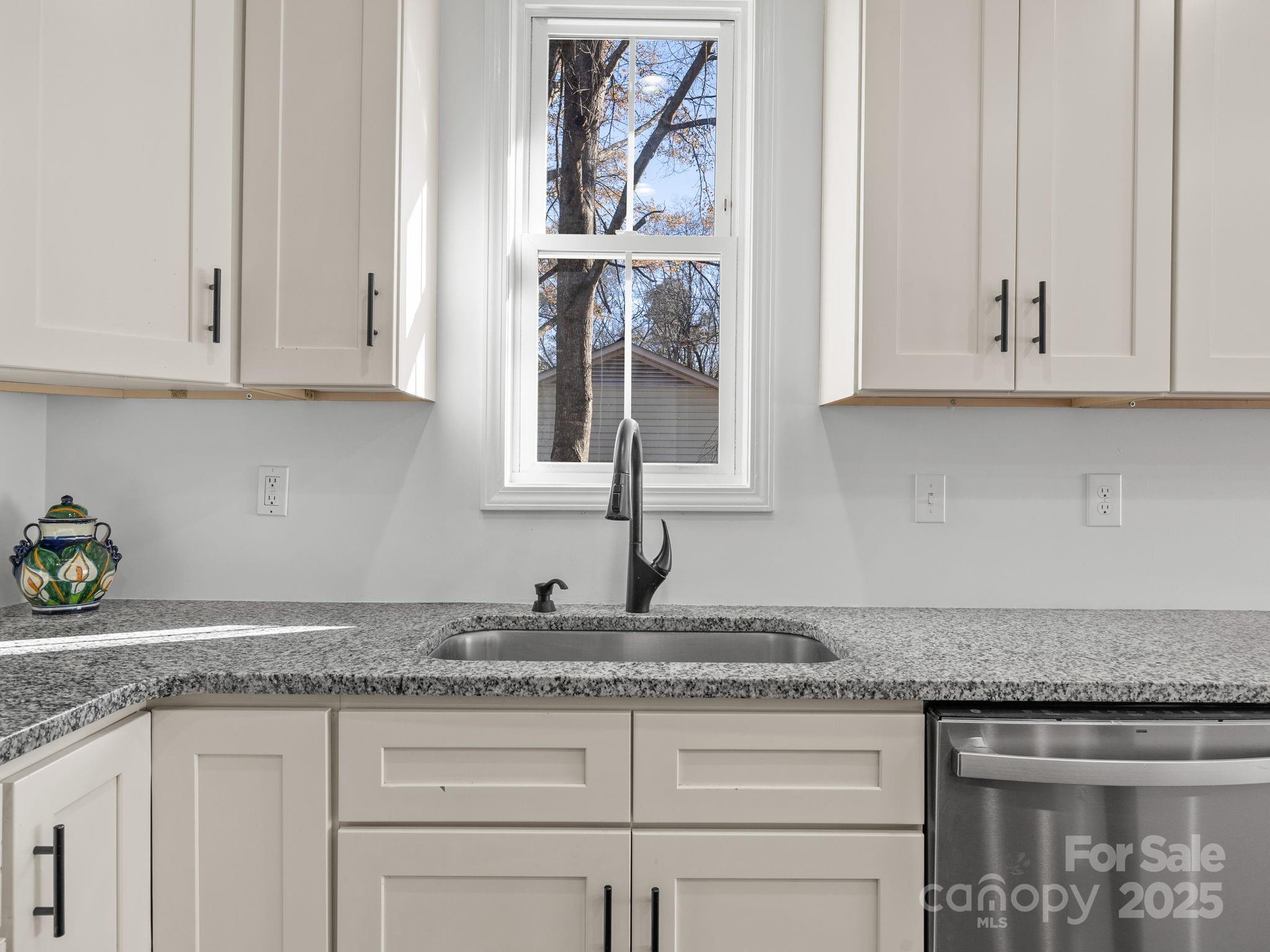 409 South Lyles Avenue Landrum, SC 29356 - Photo 13 of 36 a kitchen with granite countertop white cabinets and a window