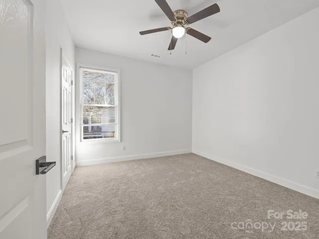 an empty room with windows and fan