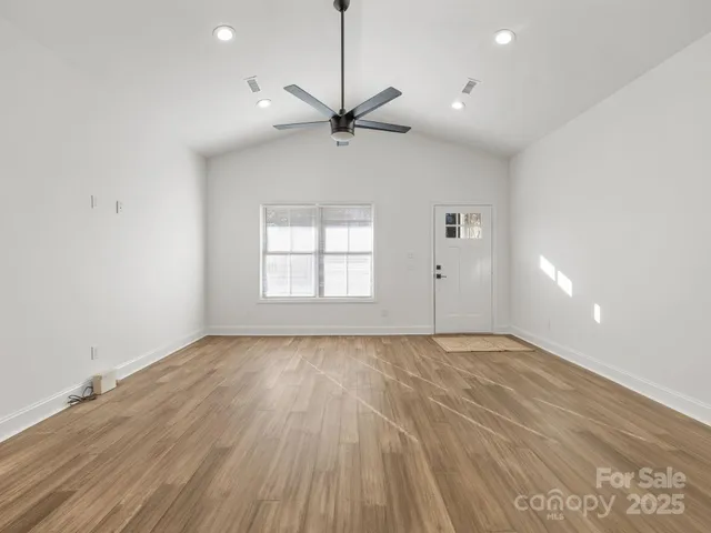 a view of an empty room with a window and wooden floor