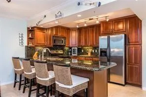 a kitchen with granite countertop a table chairs microwave and refrigerator