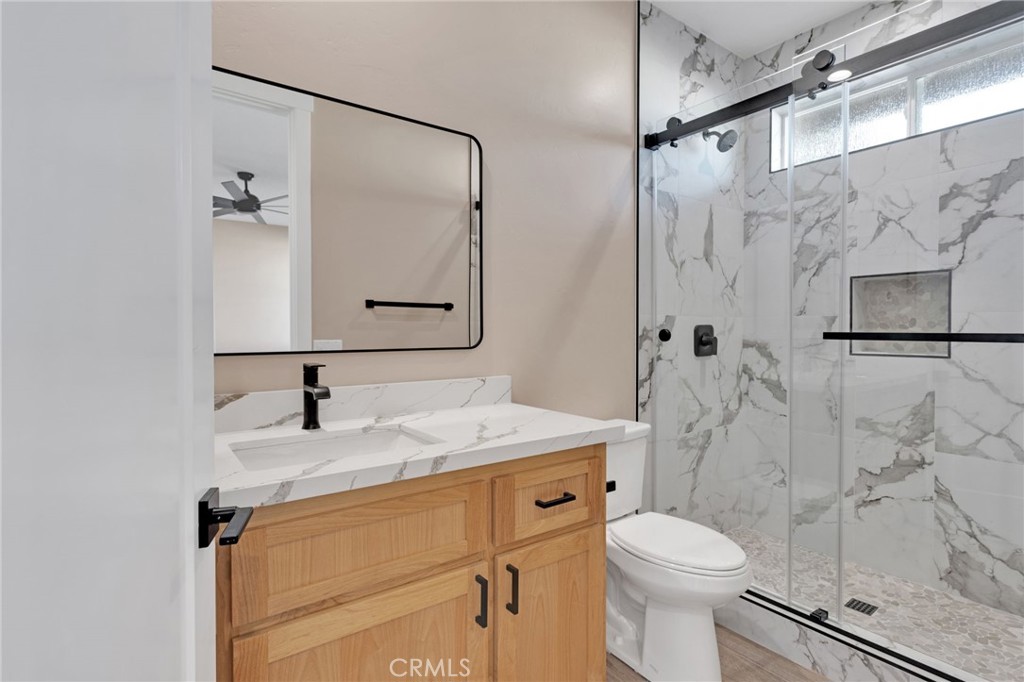 16618 Country Ranch Court Victorville, CA 92395 - Photo 19 of 31 a bathroom with a granite countertop sink toilet a mirror and shower