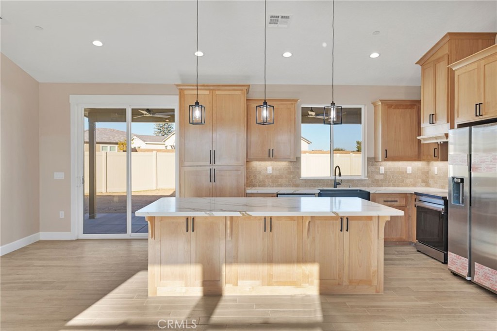 16618 Country Ranch Court Victorville, CA 92395 - Photo 6 of 31 a large kitchen with stainless steel appliances kitchen island granite countertop a sink and cabinets