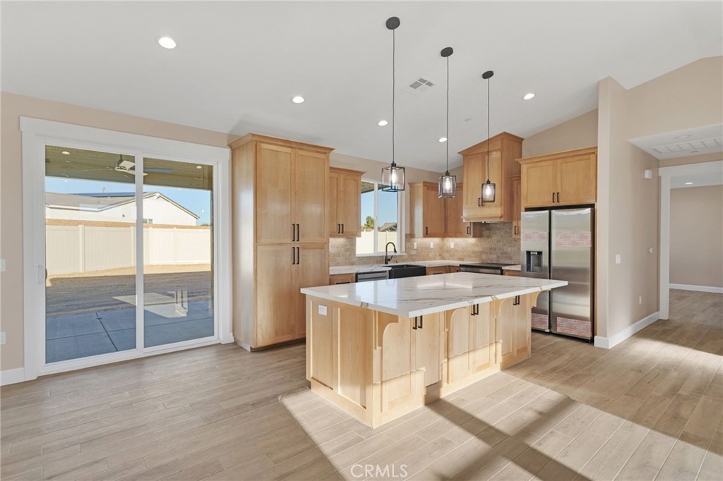 16618 Country Ranch Court Victorville, CA 92395 - Photo 7 of 31 a large kitchen with stainless steel appliances kitchen island a stove a refrigerator a sink and a dining table with wooden floor