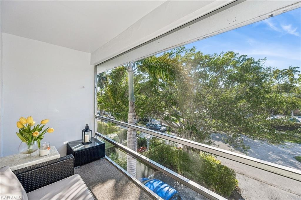 72 7th Street South, Unit 305 Naples, FL 34102 - Photo 18 of 26 a balcony with wooden floor and outdoor seating