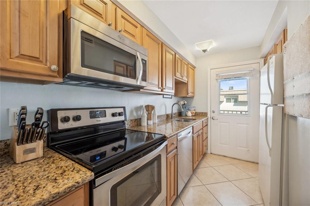 72 7th Street South, Unit 305 Naples, FL 34102 - Photo 5 of 26 a kitchen with stainless steel appliances granite countertop a stove a microwave and a refrigerator