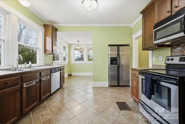 a view of an empty room with a window and a kitchen
