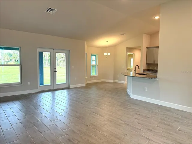 a view of an entryway of a house and empty room with wooden floor
