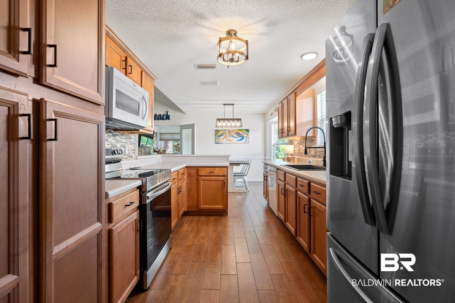 22764 Respite Lane Foley, AL 36535 - Photo 10 of 46 Kitchen with stainless steel appliances, a sink, a peninsula, decorative backsplash, and a textured ceiling