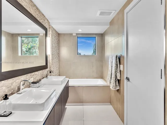 a bathroom with a tub sink and mirror