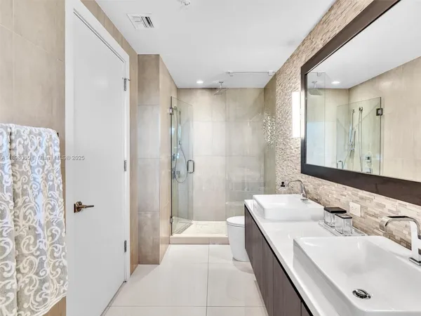 a bathroom with a double vanity sink and mirror with shower