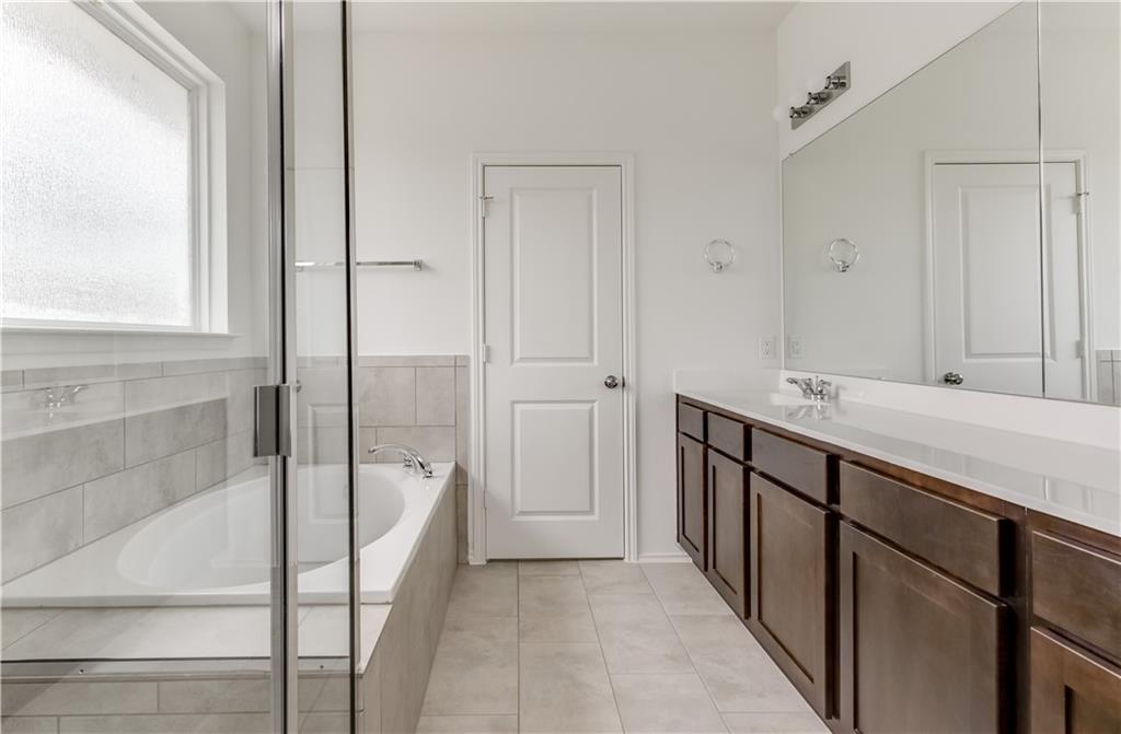 712 Affazia Lane Georgetown, TX 78628 - Photo 24 of 40 a spacious bathroom with a shower sink and mirror