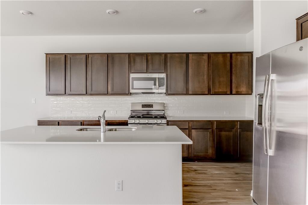 712 Affazia Lane Georgetown, TX 78628 - Photo 10 of 40 a kitchen with stainless steel appliances granite countertop a stove a sink and a refrigerator