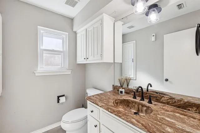 a bathroom with a granite countertop sink a mirror and a toilet